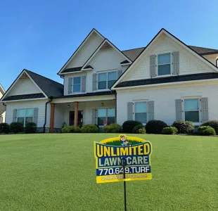 white house with Unlimited Lawn Care lawn sign in yard